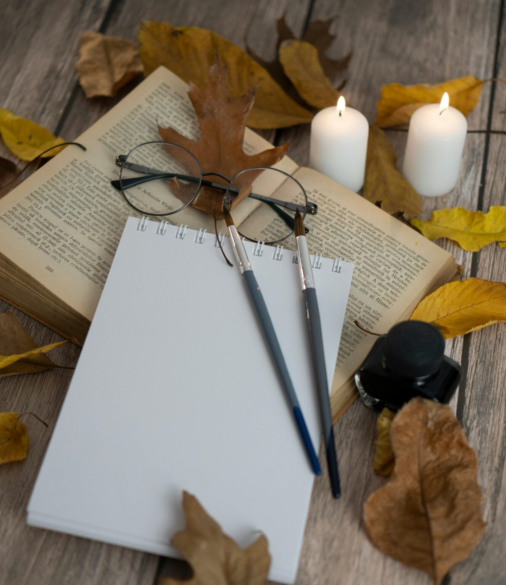 A still composition — open book, candle, ink pot, late afternoon light — the visual of an examined life as a daily practice.