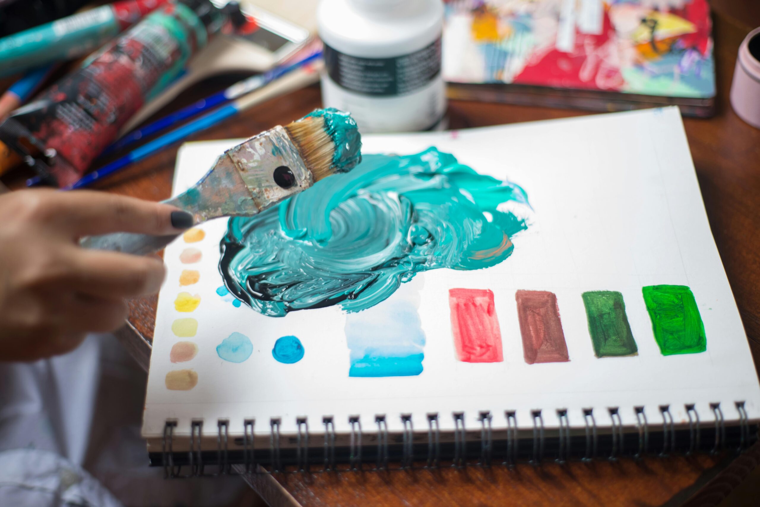 Close-up of a person mixing vibrant paints with a brush on paper. Artistic inspiration in action.