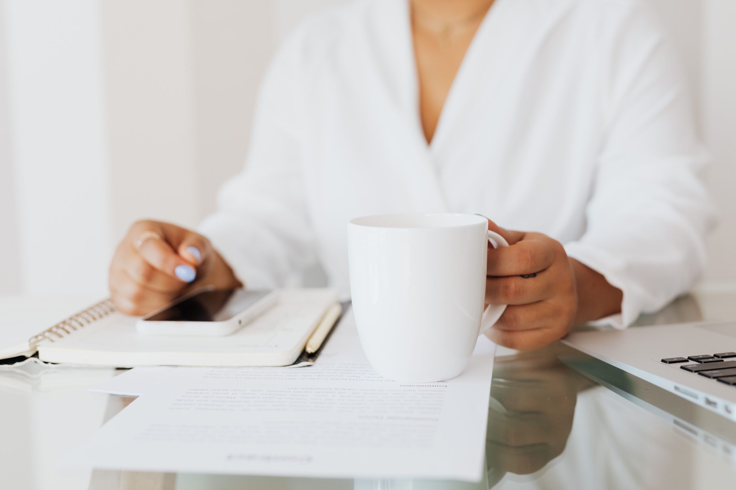 A pair of hands cradling a mug at the edge of an open notebook — the visual of a familiar place stretched, gently, one page further.